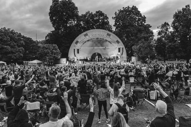 Hands raised in worship before the Gage Park bandshell