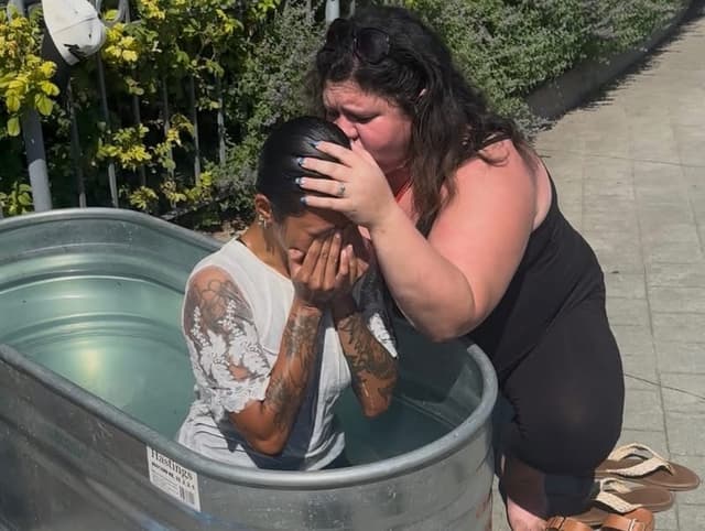 A woman held and prayed over in the baptism tank