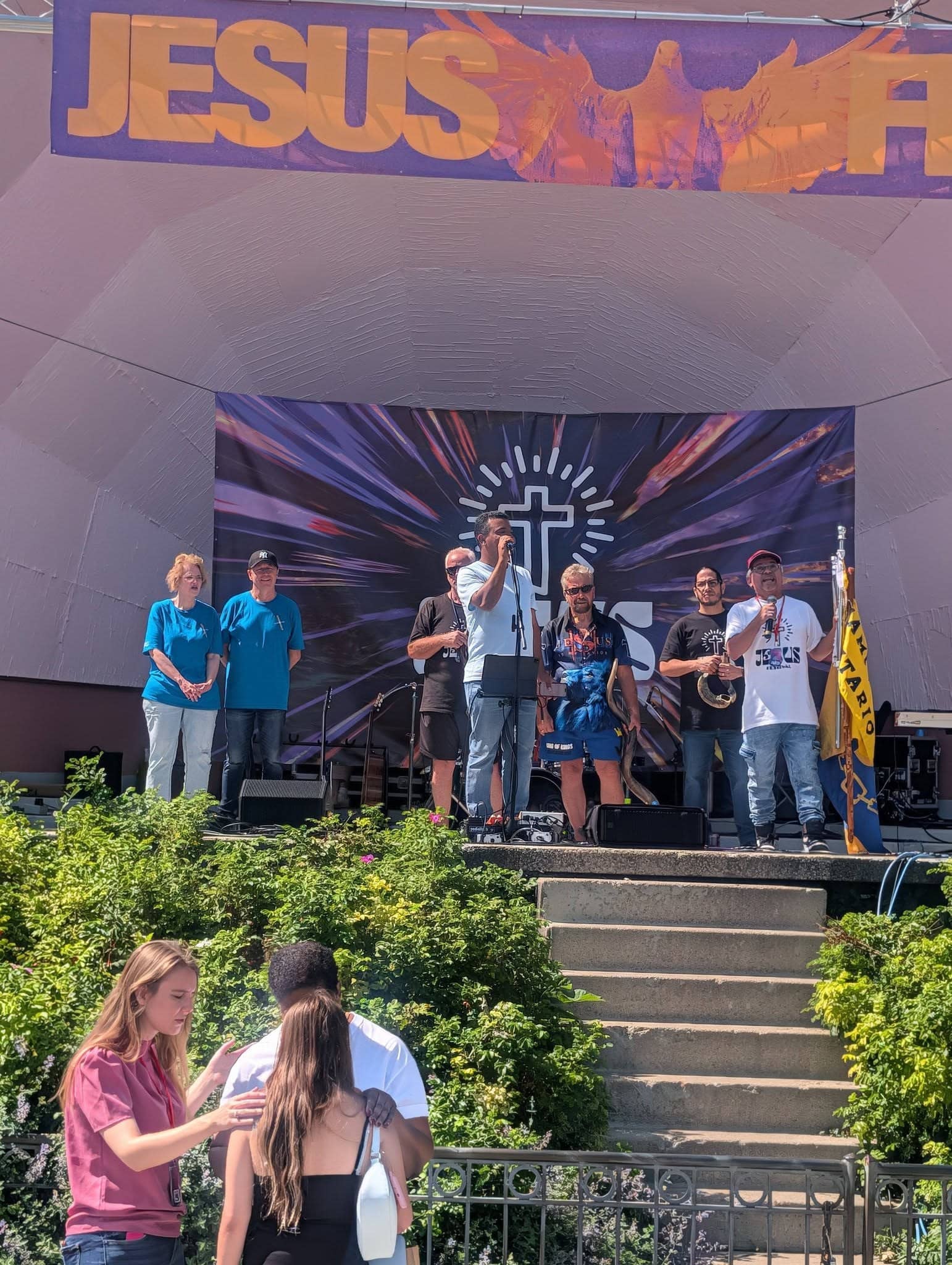 Pastors and leaders on the bandshell stage as prayer happens below, Jesus Festival Hamilton 2026