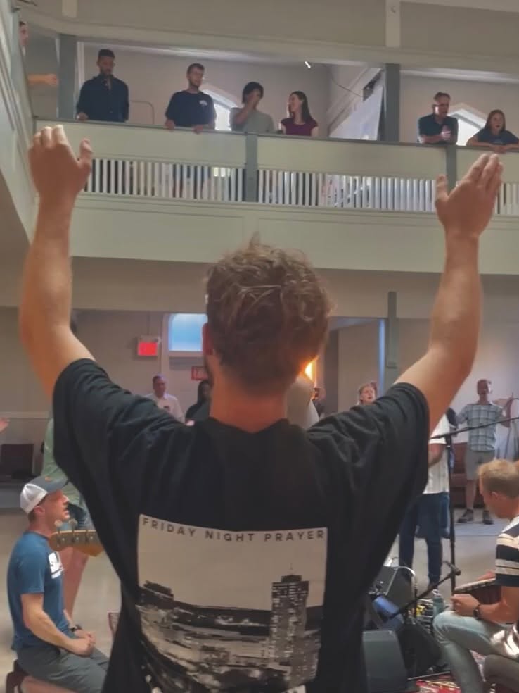 A worshipper lifting their hands at Friday Night Prayer in Hamilton